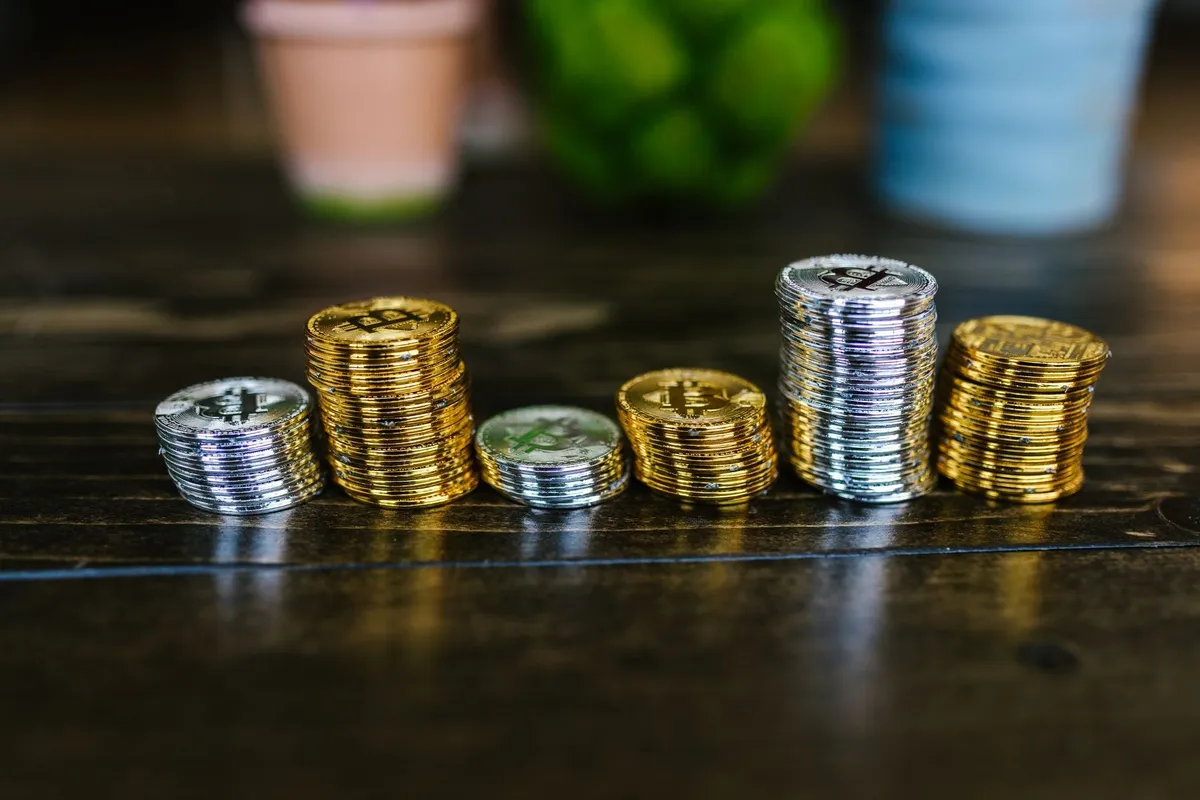 A pile of shiny gold and silver cryptocurrency coins on a wooden table, symbolizing hidden value.